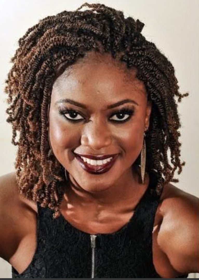 Portrait of a Black woman with dark skin, wearing brown spring twist hair, dark lipstick, black eye makeup, a black dress with a zipper, and gold earrings.